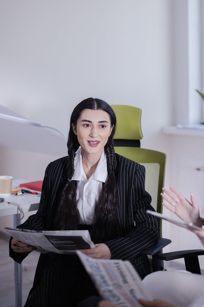 Businesswoman sitting in office reading a newspaper during a meeting.